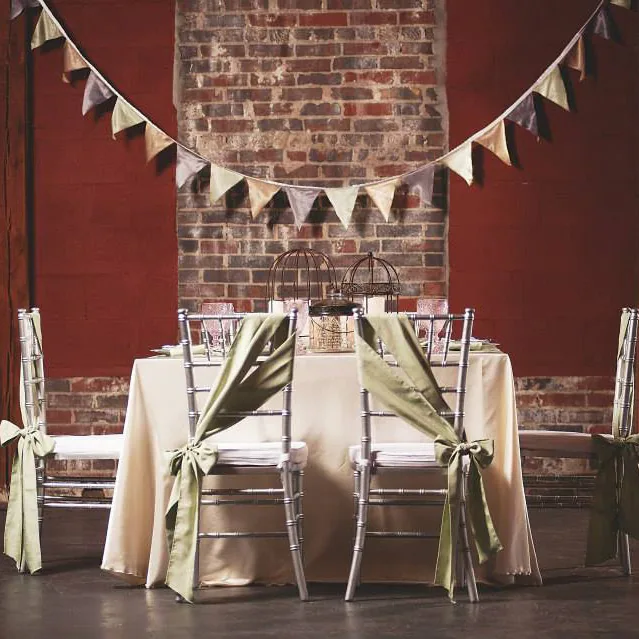 Sweetheart table with ribboned chairs against the brick wall